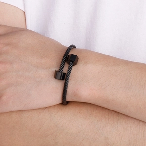 Detail of matte black industrial steel wire bracelet with hexagonal geometric ends on wrist