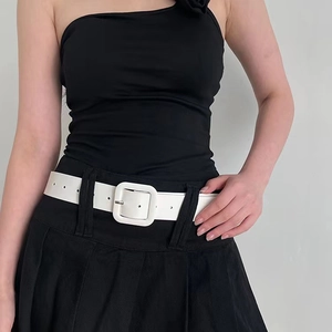 Detail of a white minimalist wide waist belt with a large square buckle on a black dress