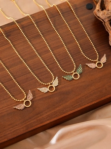 Macro view of gold angel wing pendants with colorful crystals on dark wood and silk
