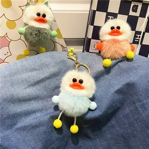Detailed view of plush duck keychains in mint green, peach pink, and sky blue on denim