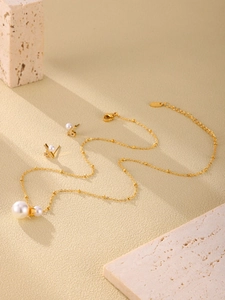 Detailed view of gold jewelry set with zircon pearl necklace and bowknot earrings