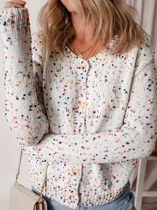 Dettaglio del cardigan in maglia grossa bianca con pois colorati e bottoni in legno