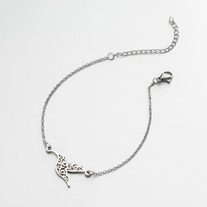 Macro view of minimalist stainless steel bracelet featuring a hollow bird pendant