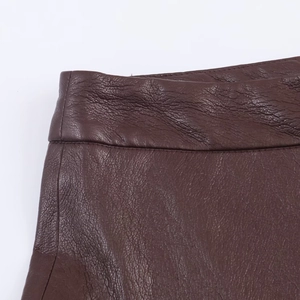 Dettaglio macro della gonna midi in ecopelle marrone scuro con trama e cuciture fini