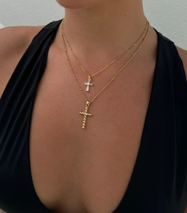Detail of layered gold titanium steel necklaces with zircon cross pendants on a model