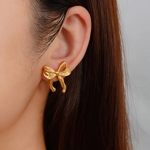 Elegant 18k gold plated titanium steel bow stud earrings shown on model ear profile