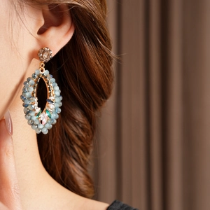 Détail de boucles d'oreilles bohèmes avec perles bleues et cristaux sur un modèle