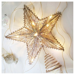 Close-up of sparkling gold 3D star tree topper with LED lights on silk fabric background