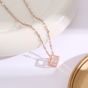 Vista macro del ciondolo a cubo in oro rosa con zirconia su un vassoio di ceramica bianca