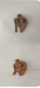 Detail of plush baby earflap hats in brown and caramel with soft pom-poms and buttons