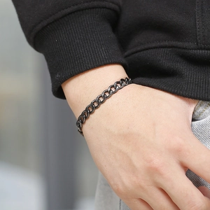 Close-up of a matte black stainless steel curb chain bracelet worn on a male wrist