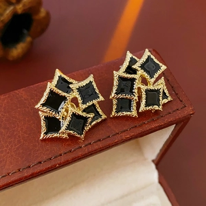 Macro shot of French vintage gold-edged black enamel square earrings with silver needles