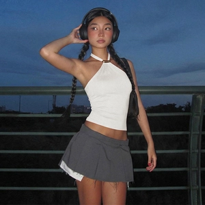 Outdoor night shot of a white backless halter top paired with a gray pleated skirt