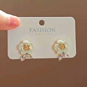 Detailed macro view of enamel flower earrings with golden rose center and leaf crystals