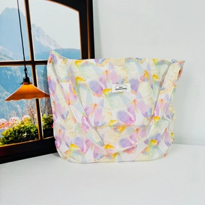 Detailed view of canvas tote bag featuring pastel butterfly patterns and stitched brand label