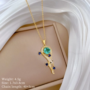 Detailed view of peacock pendant with green stone and pavé crystals on gold necklace