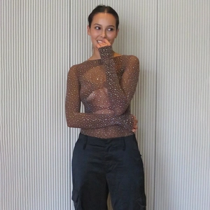 Détail du body en mesh marron transparent orné de strass brillants et manches longues