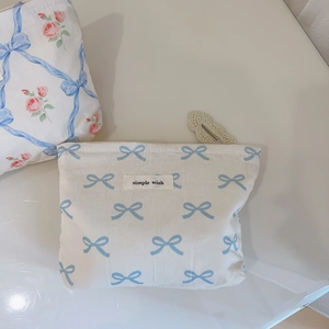 Vue détaillée d'une trousse à maquillage fleurie crème avec motifs nœuds bleus et étiquette