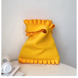 Detail of bright yellow shoulder bag with wavy pleated edges and minimalist design