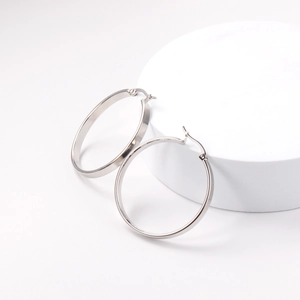 Minimalist silver stainless steel hoop earrings with a polished metallic finish on white stand