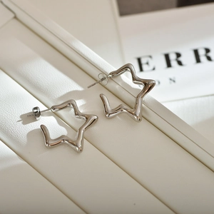 Close-up of polished silver star-shaped hoop earrings on a white textured display