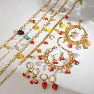 Detailed shot of fruit charms and pearls on gold stainless steel jewelry set