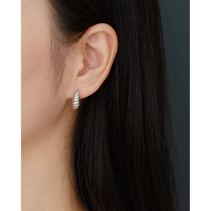 Close-up of silver horn-style ribbed earrings worn by a model for a chic metal look