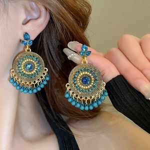 Bohemian gold earrings with blue rhinestones and dangling faux pearls on model