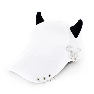 Detail of white baseball cap with black horns, silver rings, and star heart pendants