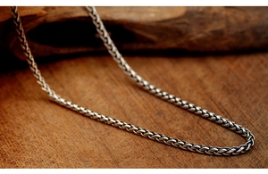 Macro shot of a polished silver titanium steel Cuban link chain necklace on wood