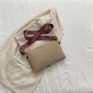 Detail view of small tan crossbody bag with colorful ethnic geometric wide shoulder strap