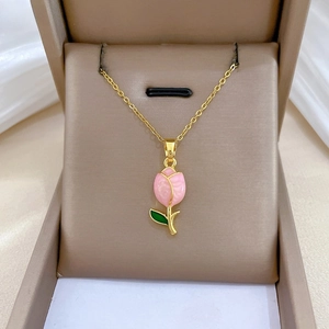 Detail of pink tulip pendant necklace with green enamel leaves on silk cushion