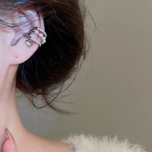 Détail d'un earcuff argenté à plusieurs rangs avec perles, strass et pendentif cœur
