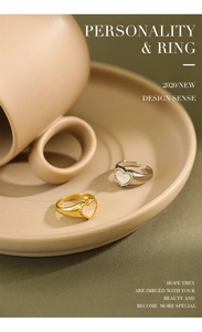 Macro shot of heart-shaped shell inlay rings in gold and silver on ceramic saucer