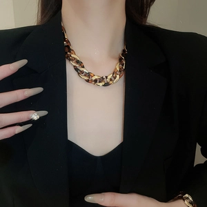 Close-up of leopard print resin and gold chain necklace worn on a black suit blazer