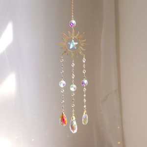 Detail of golden sun and star pendant with teardrop crystal prisms reflecting rainbow light
