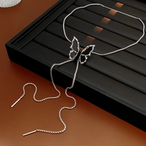 Detailed view of silver butterfly necklace with woven chain on a black display stand