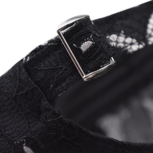 Macro view of adjustable silver metal buckle and black floral lace strap on baseball cap