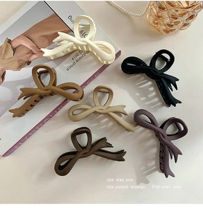 Detailed set of matte bow hair claws in cream, brown, and black displayed on a minimal desk