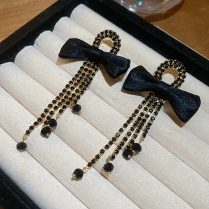 Detail of black bow earrings with crystal tassels and gold-tone base in a jewelry box