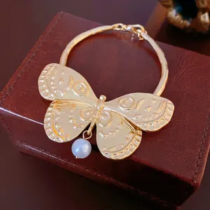 Chic gold butterfly cuff bracelet with a pearl charm on luxury leather padding