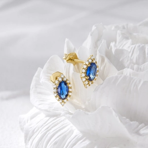 Detailed close-up of S925 sterling silver earrings with blue cat-eye stone on white flower
