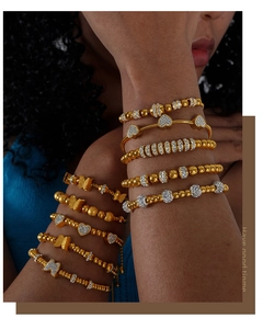 Gros plan détaillé de bracelets superposés dorés avec des perles de cœur et de papillon