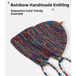 Detailed view of rainbow striped knit beanie with handmade crochet texture and earflaps