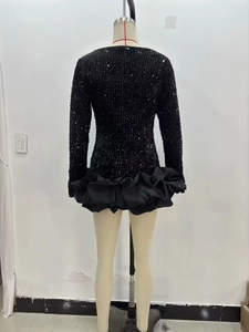 Détail du dos d'une robe noire à sequins et manches longues avec ourlet à volants bouffants