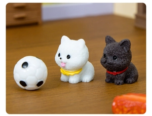 Close-up of mini puppy figurines with a small soccer ball on a wooden surface