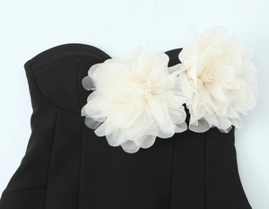 Dettaglio dell'abito a fascia nero con due fiori decorativi 3D in mesh bianco crema