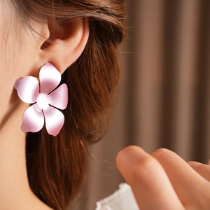 Gros plan de boucles d'oreilles fleurs rose mat avec pétales dégradés sur un mannequin