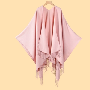 Detail view of pink knitted shawl featuring elegant tassel fringe and soft fabric texture