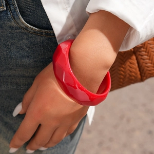 Close-up of chunky red resin geometric bangle with faceted surface on a model's wrist